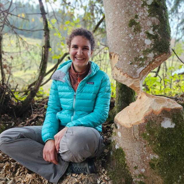 Cécile Auberson - info fauna Femme à côté d'un tronc d'arbre avec des traces de castor